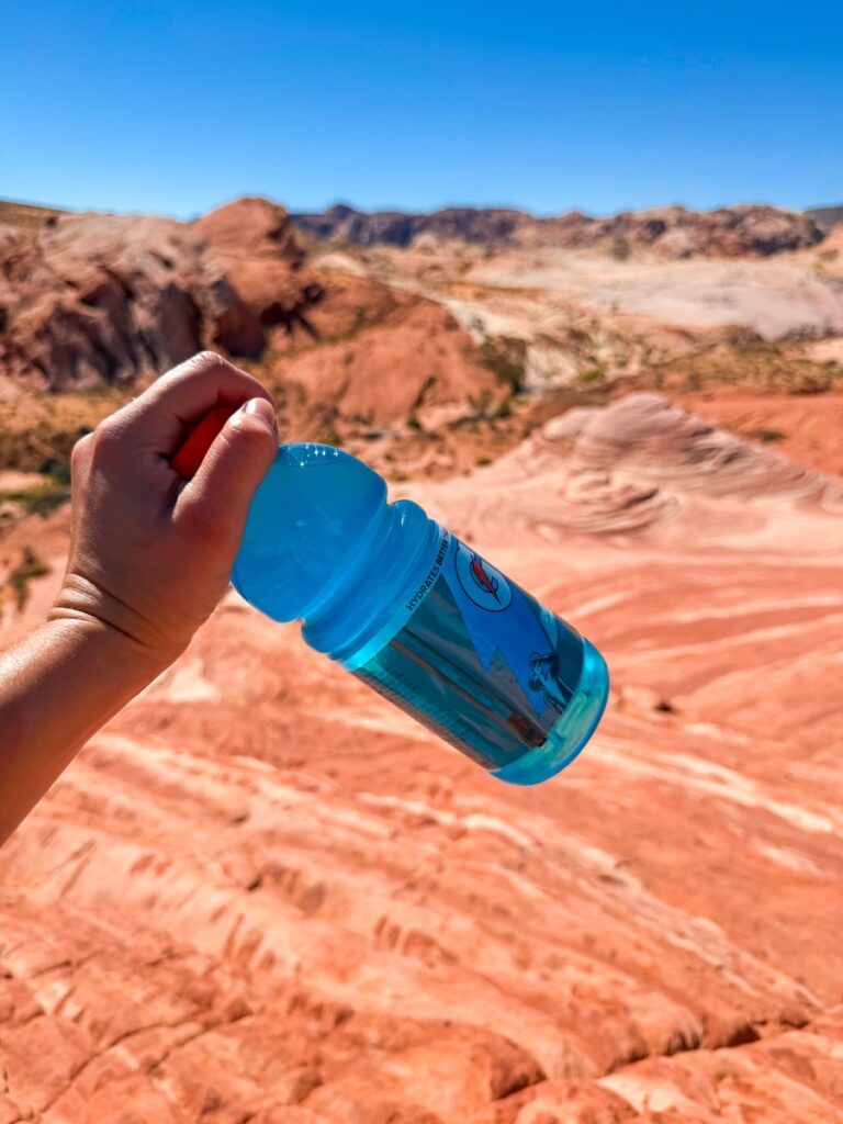 Holding an electrolyte drink while hiking in the heat of the Valley of Fire