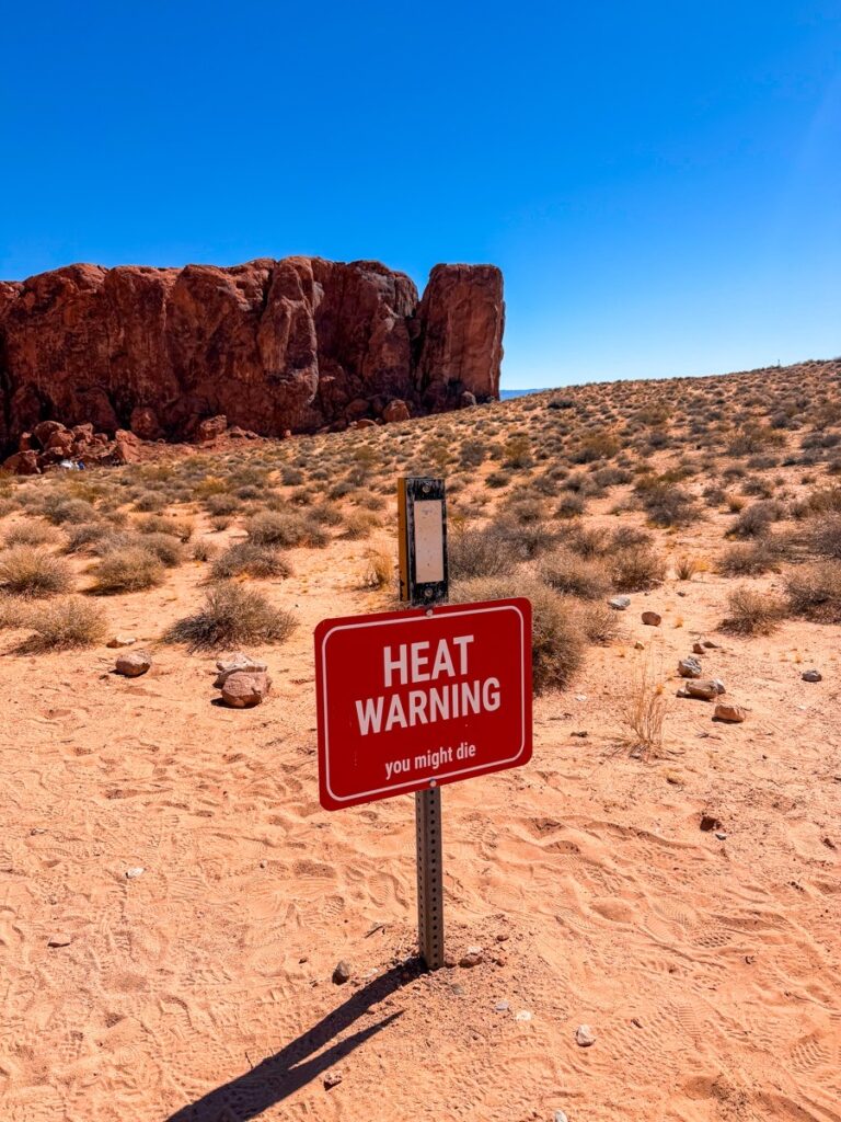 A red heat warning sign in the desert sand at the Valley of Fire State Park, Nevada